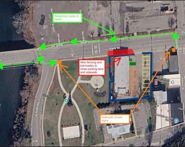 Aerial map shows Park St. with green arrows for pedestrian route, orange arrows for new fencing, barricades, and sidewalk closures, and yellow lines for parking spaces. Labels indicate closures and directions.
