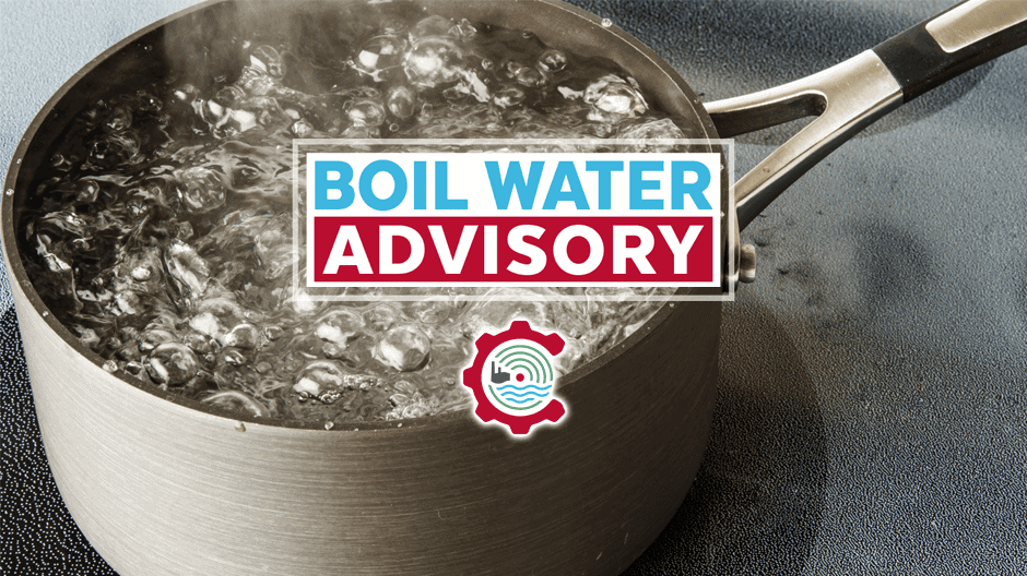 A pot of water boiling on a stove with a sign that reads Boil Water Advisory overlaid on the image.