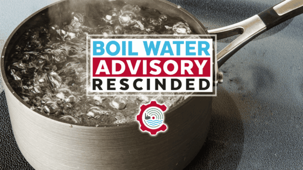 A pot of water boiling on a stovetop with a sign overlay that reads, Boil Water Advisory Rescinded, indicating the advisory has been lifted.