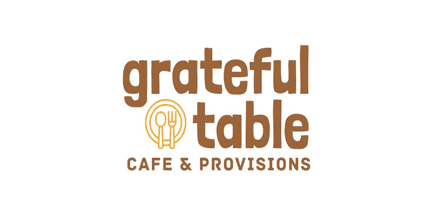 Logo for grateful table cafe & provisions in brown text with a plate, fork, and spoon graphic inside the letter a of grateful on a white background.