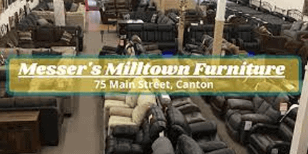 A furniture store showroom with sofas and chairs on display. A transparent banner reads Messers Milltown Furniture, 75 Main Street, Canton.