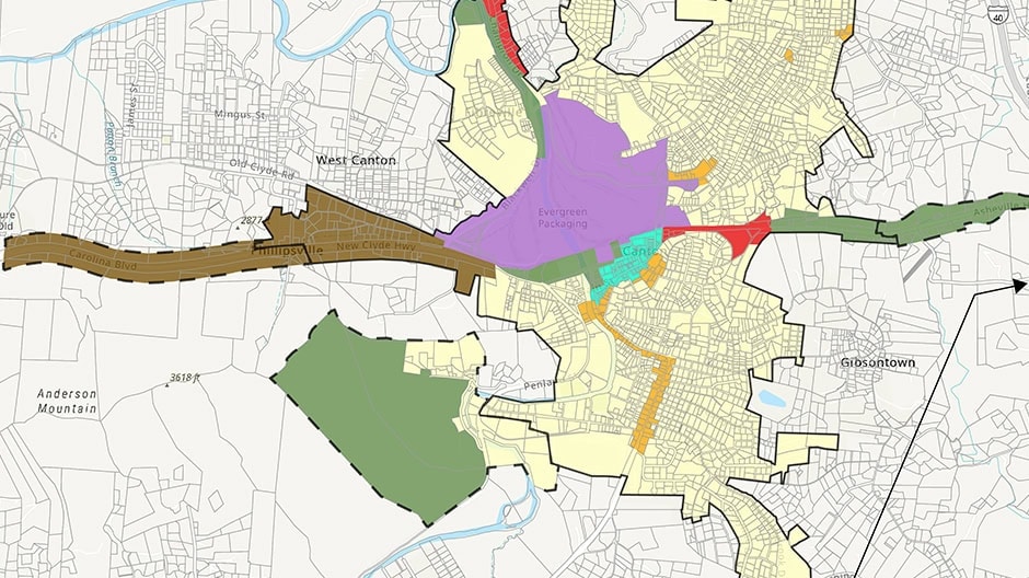 A map showing a city with different regions highlighted in colors like purple, green, orange, and brown, representing zoning or planning areas. Streets, neighborhoods, and borders are detailed in black lines.