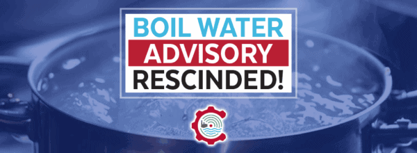 A pot of boiling water with a sign stating Boil Water Advisory Rescinded! in bold blue, red, and black letters, and a water-related logo below the text.
